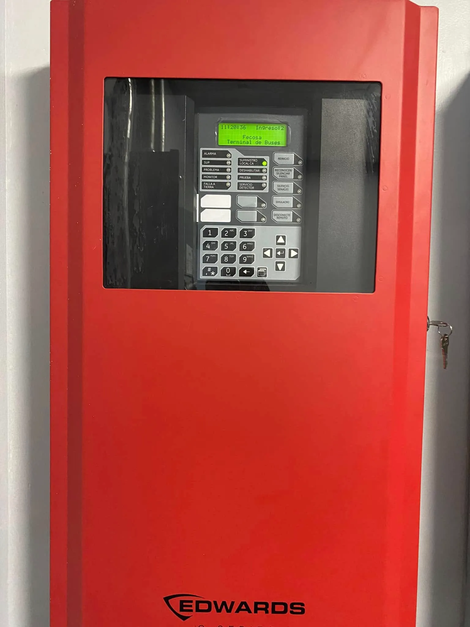 Panel de alarma de incendios instalado en la Terminal de Buses Fecosa, con la pantalla encendida indicando estado normal